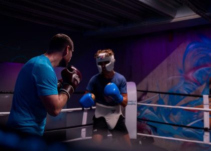 Two male boxers engaged in training in an indoor boxing ring with colorful graffiti.